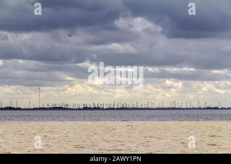 Dramatische beleuchtete Küstenlandschaft, darunter ein entfernter Windpark bei Neuharlingersiel in Ostfriesland Stockfoto