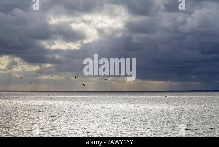 Dramatische beleuchtete Küstenlandschaft, darunter einige Kitesurfer bei Neuharlingersiel in Ostfriesland Stockfoto