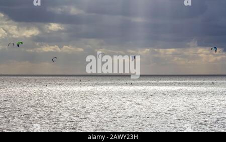 Dramatische beleuchtete Küstenlandschaft, darunter einige Kitesurfer bei Neuharlingersiel in Ostfriesland Stockfoto