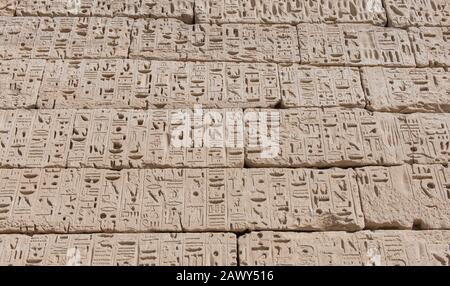 Hieroglypische Schnitzereien an der Wand am altägyptischen Tempel von Medinat Habu in Luxor Stockfoto