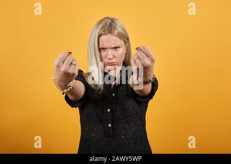 Mädchen im schwarzen Kleid wütende irritierte Frau hält ihre Hände in Fäusten geklungen Stockfoto