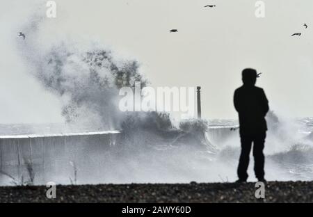 Shoreham UK, 10. Februar 2020 - EIN Wanderer beobachtet, wie die Wellen am Eingang des Shoreham Harbour in Sussex einbrechen, während das Schlussende von Storm Ciara nach und nach durch Großbritannien bläst, nachdem er am Wochenende den Großteil des Landes gebeutelt hatte: Credit Simon Dack/Alamy Live News Stockfoto