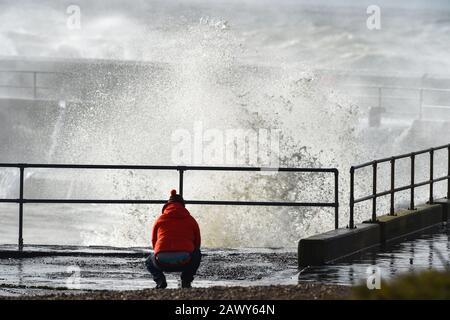 Shoreham UK, 10. Februar 2020 - EIN Wanderer beobachtet, wie die Wellen am Eingang des Shoreham Harbour in Sussex einbrechen, während das Schlussende von Storm Ciara nach und nach durch Großbritannien bläst, nachdem er am Wochenende den Großteil des Landes gebeutelt hatte: Credit Simon Dack/Alamy Live News Stockfoto