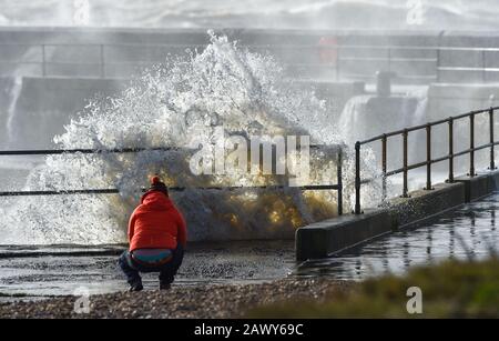 Shoreham UK, 10. Februar 2020 - EIN Wanderer beobachtet, wie die Wellen am Eingang des Shoreham Harbour in Sussex einbrechen, während das Schlussende von Storm Ciara nach und nach durch Großbritannien bläst, nachdem er am Wochenende den Großteil des Landes gebeutelt hatte: Credit Simon Dack/Alamy Live News Stockfoto