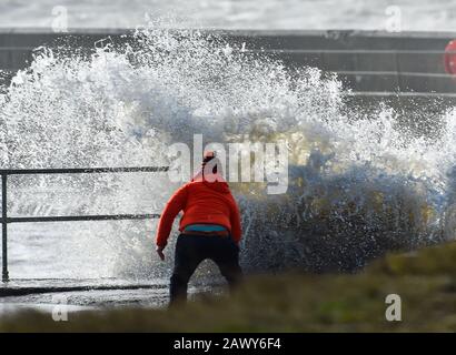 Shoreham UK, 10. Februar 2020 - EIN Wanderer beobachtet, wie die Wellen am Eingang des Shoreham Harbour in Sussex einbrechen, während das Schlussende von Storm Ciara nach und nach durch Großbritannien bläst, nachdem er am Wochenende den Großteil des Landes gebeutelt hatte: Credit Simon Dack/Alamy Live News Stockfoto