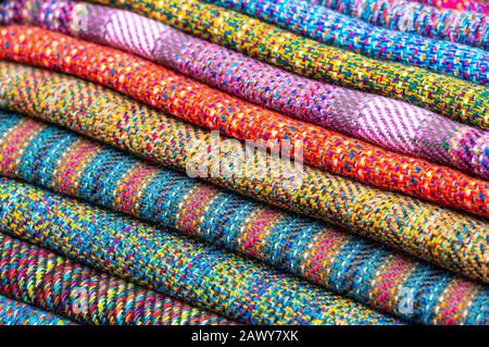 Ein Haufen bunter traditioneller Anden-Textilien auf dem lokalen indigenen Markt Otavalo, Ecuador. Diese Art von Stoffen findet man in Bolivien und Peru. Stockfoto