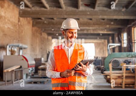 Ingenieur in Schutzkleidung mit Blick auf das Tablett Stockfoto