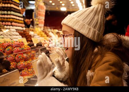 Süßes Mädchen in der Nähe eines süßen Stativs mit Schokoladenkäuzen Stockfoto