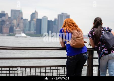New York, USA - 7. Juni 2019: Eine junge Frau von der Liberty Island blickt auf die Skyline von Manhattan Stockfoto