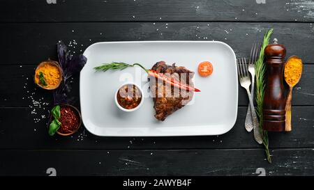 Schweinesteak mit Grillsoße. In der Platte. Auf Holzgrund. Draufsicht. Freier Speicherplatz für Ihren Text. Stockfoto