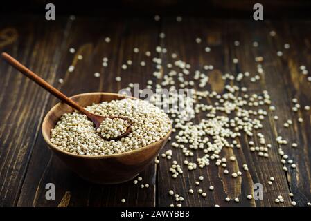 Holzschale mit Sorghumkorn und Löffel auf dunklem Holztisch Stockfoto