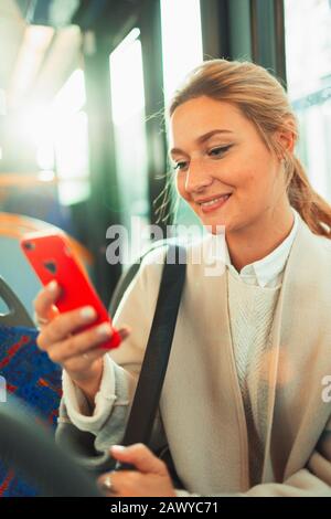 Junge Frau mit Smartphone im Bus Stockfoto