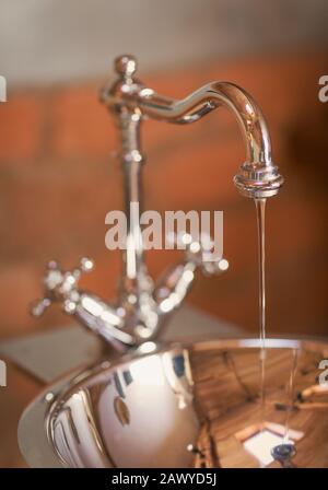 Schließen Sie das Wasser, das aus dem Edelstahlwaschbecken und -Becken fließt Stockfoto