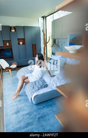 Frau in Handtuch gewickelt, im Bett im modernen Schlafzimmer entspannend Stockfoto