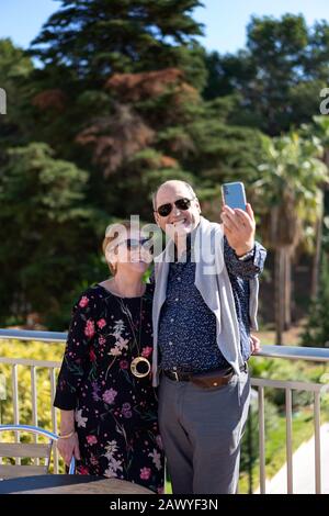 Ein Paar im Ruhestand auf der Außenterrasse, das seine freie Zeit beim Fotografieren genießt Stockfoto