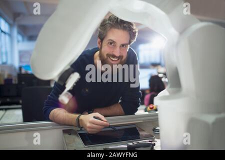 Hochformatiger Techniker mit digitalem Tablet-PC-bedientem Roboterarm Stockfoto