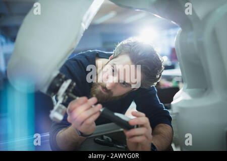 Konzentrierter Außeningenieur mit Schraubendreher zur Befestigung des Roboterarms Stockfoto