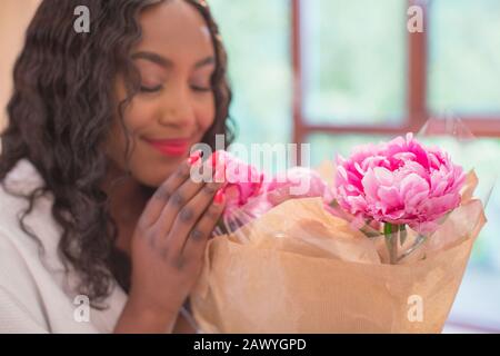 Junge Frau riecht frischen pinkfarbenen Blumenstrauß Stockfoto