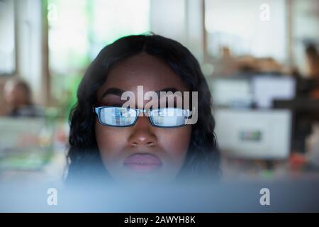 Fokussierte junge Geschäftsfrau in Brillen, die am Computer arbeiten Stockfoto