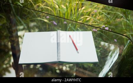 Öffnen Sie das leere Notizbuch und den Bleistift auf dem Glastisch Stockfoto