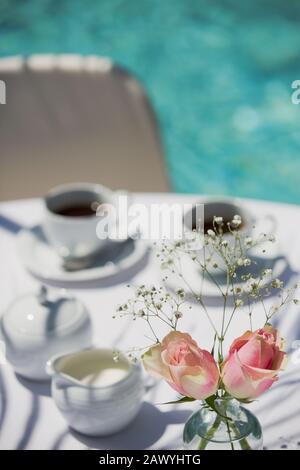 Rosen und Kaffee auf dem sonnigen Terrassentisch Stockfoto