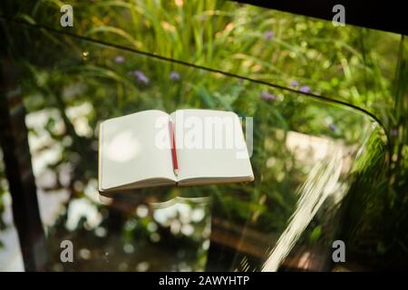 Notizbuch für leere Seiten auf dem Glastisch geöffnet Stockfoto