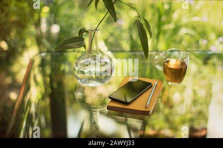 Tee und Smartphone auf dem Tisch mit Notizbuch und Vase Stockfoto