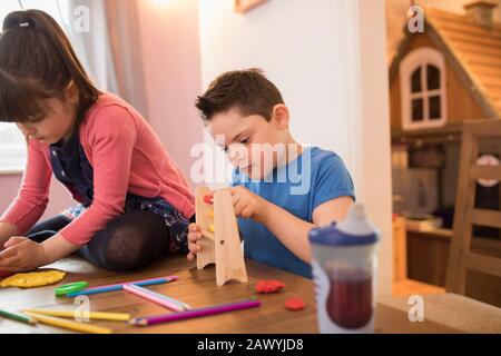 Fokussierter Junge mit Down-Syndrom, der mit Spielzeug am Tisch spielt Stockfoto