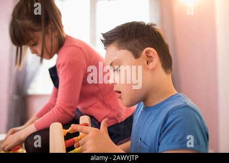 Neugieriger Junge mit Down-Syndrom, der mit Spielzeug spielt Stockfoto