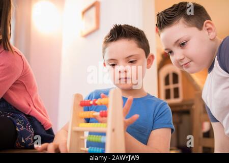 Junge mit Down-Syndrom und Bruder, der mit Spielzeug spielt Stockfoto