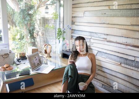 Portrait selbstbewusste junge Frau mit Smartphone im Büro Stockfoto