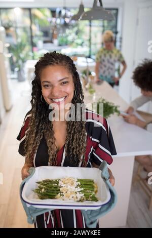 Portrait fröhliche Frau beim Kochen von Spargel in der Küche Stockfoto