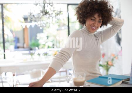 Fröhliche junge Freiberuflerin, die in der Küche arbeitet Stockfoto