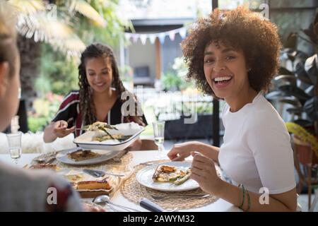 Portrait fröhliche junge Frau beim Mittagessen mit Freunden am Tisch Stockfoto