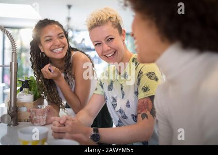 Fröhliche junge Frauenfreunde lachen und reden in der Küche Stockfoto