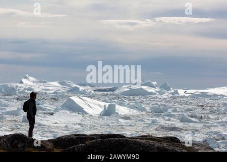 Silhouettierter Mann mit Blick auf die Eisschmelze Grönlands Stockfoto