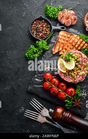 Beef Steak Tatar mit rohem Eigelb, Avocado, Kapern und Zwiebeln. Französische Küche. Draufsicht. Freier Speicherplatz für Ihren Text. Stockfoto