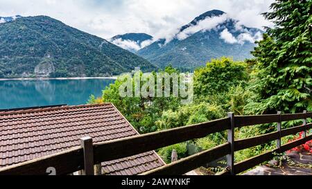 Bezaubernder Blick auf den Bergsee Ledro von einem Wanderweg in den Bergen. Postkarte mit Blick auf den Bergsee Ledro und die Alpen im Nebel Stockfoto