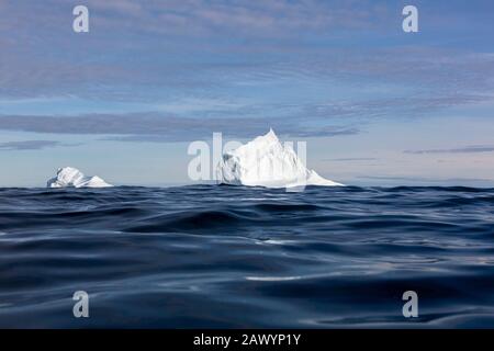 Majestätische Eisberg-Formationen über dem sonnigen blauen Ozean Stockfoto