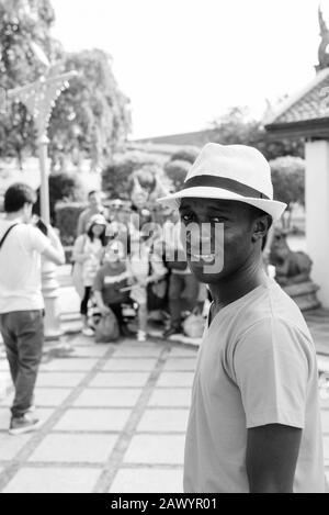 Junger glücklicher afrikanischer Tourist lächelt am Wat Arun Tempel Stockfoto