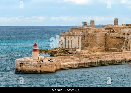 Red Old Lighthouse im Grand Harbour und der Wellenbrücke, Fort Ricasoli aus Valletta auf Malta, Insel des Mittelmeers Stockfoto