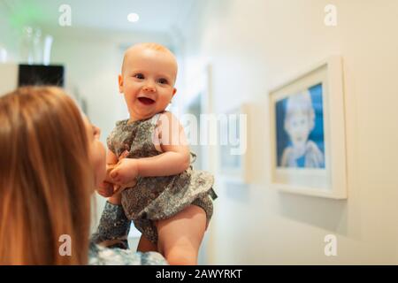 Mutter hält fröhliches süßes Mädchen auf dem Flur Stockfoto