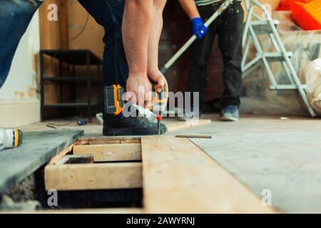 Bauarbeiter mit Leistungsbohrer, der Dielen an der Baustelle installiert Stockfoto
