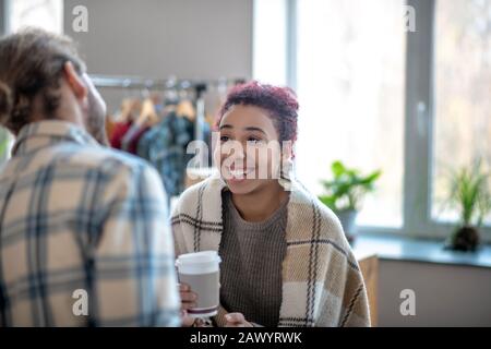 Lachende junge Mulatto Mädchen mit Kaffee in den Händen. Stockfoto