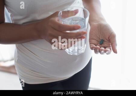 Schließen Sie schwangere Frauen, die Vitamin mit Wasser nehmen Stockfoto