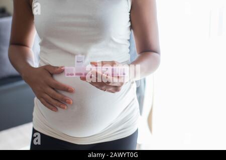 Schließen Sie schwangere Frauen mit Pillenbox, die Vitamine enthält Stockfoto