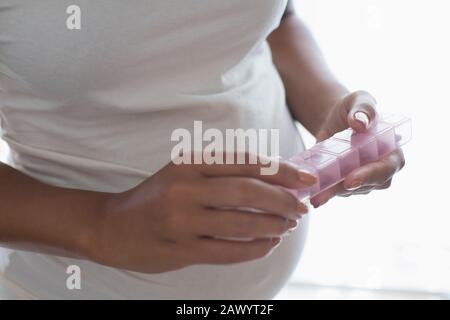 Schließen Sie schwangere Frauen mit Pillenbox, die Vitamine enthält Stockfoto