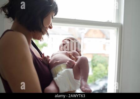 Mutter hält süßen neugeborenen Jungen am Fenster Stockfoto