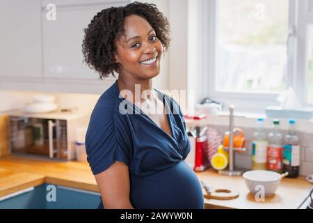 Portrait fröhliche schwangere Frau in der Küche Stockfoto