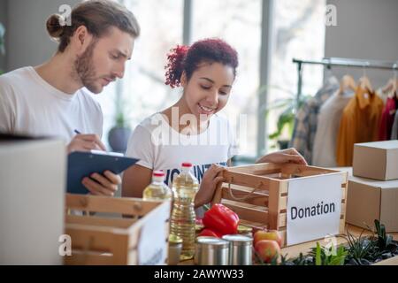 Lächelndes junges Mädchen und ernsthafter Mann mit Ordner arbeiten zusammen. Stockfoto